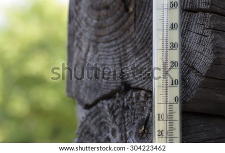 Old mercury thermometer indicating  a high temperature, concept of climate change, outdoor shot with blurred background