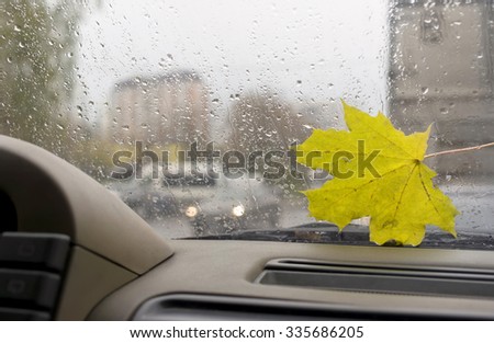 Rain on car window and urban scene in the blurred background on a gloomy winters day