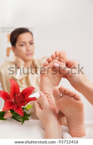 Hands of a reflexologist doing reflexology treatment on the soles of a womans feet