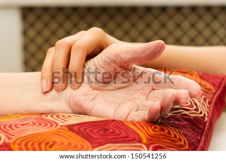 Young hands caring for old hands on a red cushion