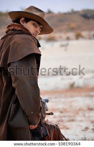 handsome cowboy in specific clothing with weapon. outdoor shot