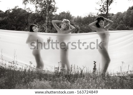 three girls wrapped in white fabric. outdoor shot