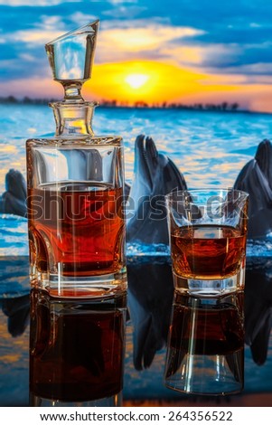 bottle of whiskey on a background of dolphins swim at sunset