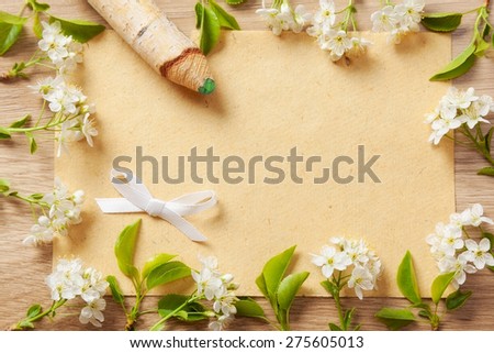 beautiful flowers cherry on branches with a pencil and a sheet of paper texture on the background of wood texture.
