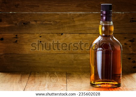 bottle  of whiskey  on a wooden background made with vintage tones