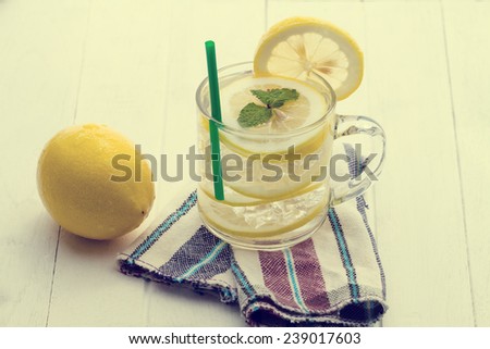 Cold lemonade with ice and mint placed on wooden floors white, made with vintage tones