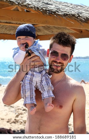 Baby boy with father having fun on vacation at sea. Happy father and son playing at the beach in the day time