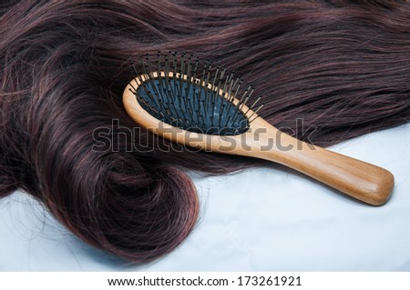 Shiny brown hair with comb on white background
