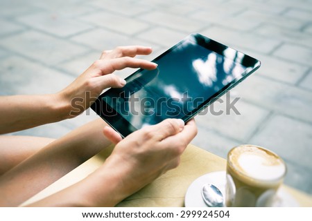 Woman using digital tablet in coffee shop. girl holding a tablet. Close up to view young woman\'s hands hold tablet