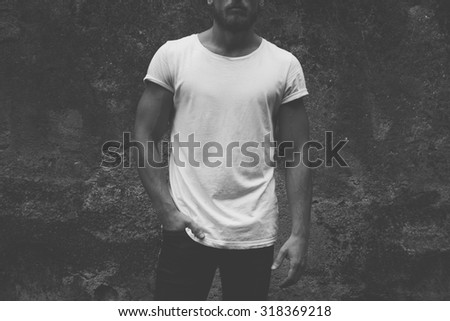 black and white photo. blank white t-shirt on muscle young man, dark concrete background