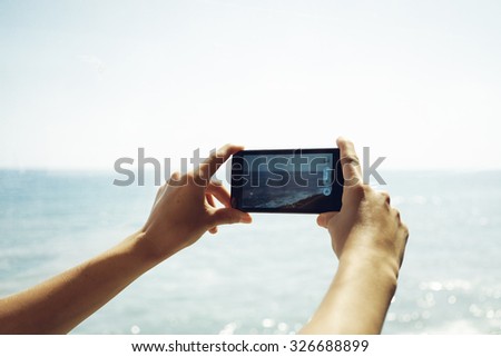 Detail view of a young woman hands holding a smart-phone device up and taking photos