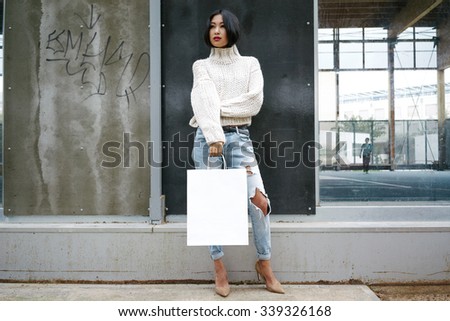 Young Asian girl holding shopping bags in one hand(mock up to paste a logo)