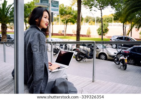 Beautiful business woman with computer laptop working outside looking at screen in business district