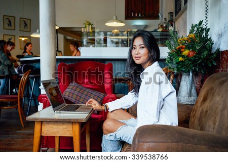 Young beautiful Asian business woman at a coffee shop working on a laptop