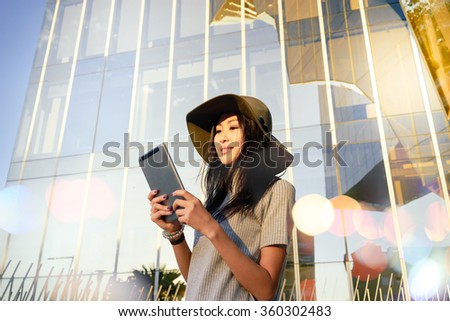 Pretty young smiley Asian businesswoman uses modern tablet outside the office. portrait of a beautiful Asian female hipster recorded a video for her video blog