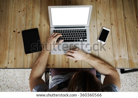 Top view shot of a male hipster using notebook with blank copy space screen for your information. Digital tablet and smart-phone on the wood table