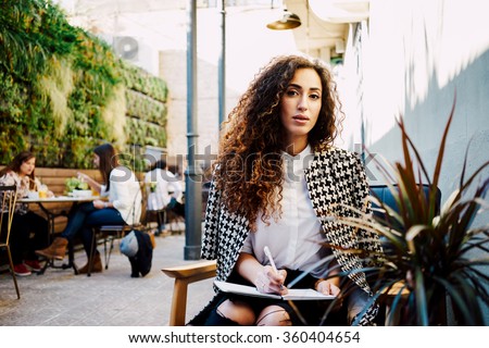 Young attractive business woman with long curly hair holds a job interview in a coffee-shop.beautiful girl takes a journalist interviews
