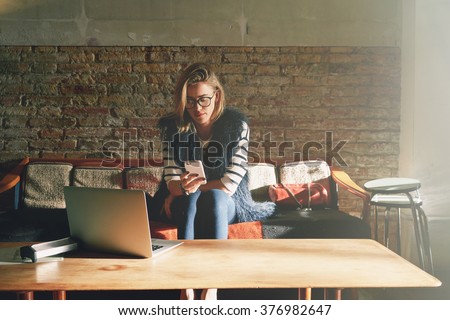 young beautiful businesswoman writes a message on her smart-phone during the lunch break. Attractive female student doing homework in a coffee-shop