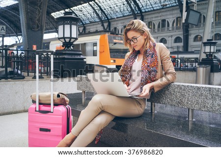 Beautiful young blonde female student using portable laptop computer. modern businesswoman using a laptop computer while waiting for the train
