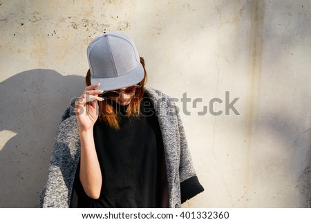 Female model wearing a black blank cap and sunglasses looking away. Portrait of a young beautiful girl with cap