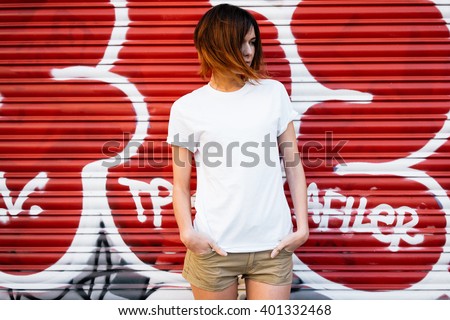 young attractive girl wearing a white t-shirt standing on a graffiti wall background