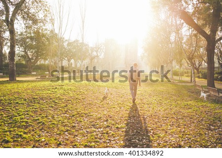 a young man walking with a dogs in the park at sunset