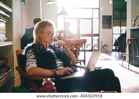 young attractive female student preparing for the exam using laptop while as drinking tea in a cafe. beautiful business woman using a laptop for the distance learning
