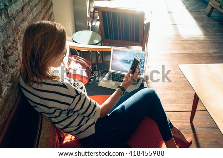 Attractive female student chatting with her friends  while sitting front open computer in vintage coffee shop. Young modern business woman working remotely over a new start-up project.