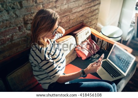 Attractive female freelancer chatting with her friends  while sitting front open computer in vintage coffee shop. Young modern business woman working remotely over a new start-up project.