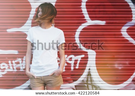 young attractive girl wearing a white t-shirt posing on a graffiti wall background