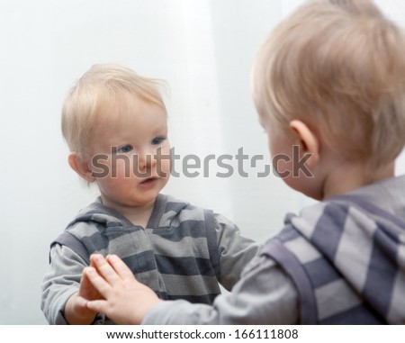 Small child looking to mirror at his face.