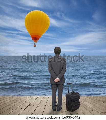 man with a suitcase observes balloon