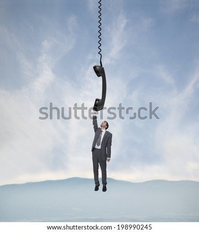 young businessman hanging on the telephone handset over the landscape