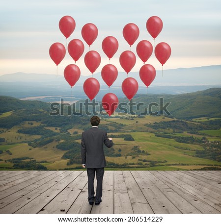 young businessman with a red heart-shaped balloons in the landscape