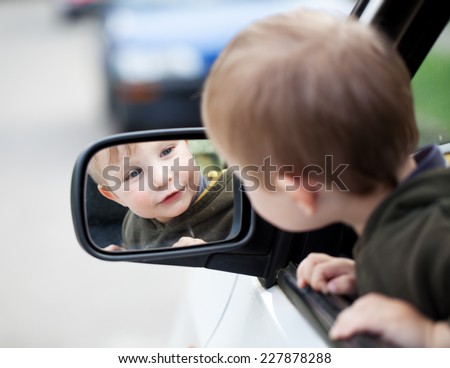 Small child looking to outside mirror