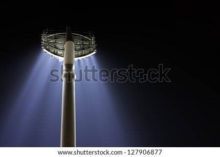 A single pole of stadium lights cast blue beams downward at night
