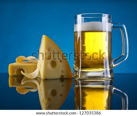 beer, cheese and chips on a blue background with a mirror