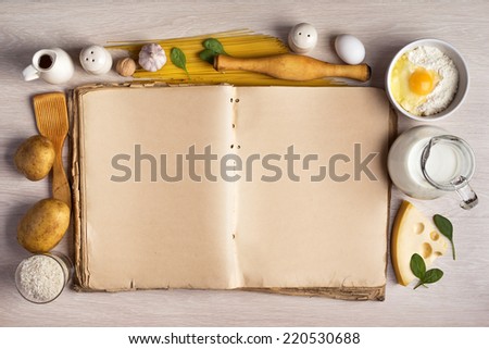 vintage cook book and ingredients for the food recipe around in a frame on the background of the table