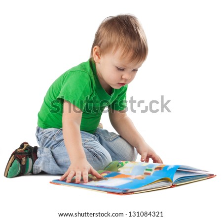 Enthusiastic little boy with a book sitting on the floor, isolated on white