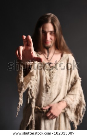 Handsome asian man with long hair makes a gesture blessing.