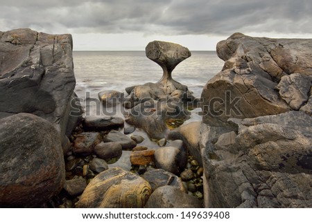 norway, Unusual stone in Atlantic ocean coast. View on Kannesteinen and Kvalheimsvika. Over thousands of years, ocean waves have ground the rock to the special shape it has today.