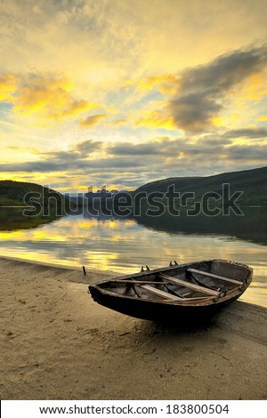 A small boat on the lake, in the rays of the setting sun, Norway