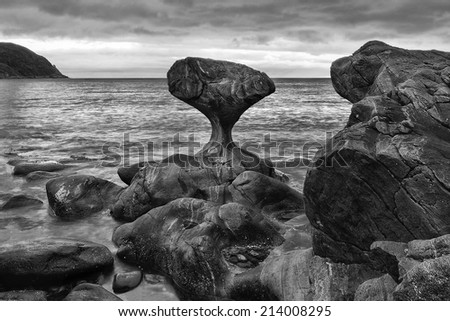 norway, Unusual stone in Atlantic ocean coast. View on Kannesteinen and Kvalheimsvika. Over thousands of years, ocean waves have ground the rock to the special shape it has today. black and white