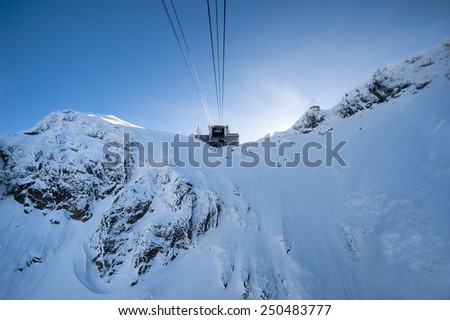 Ski lift carrying skiers up to the clear blue sky