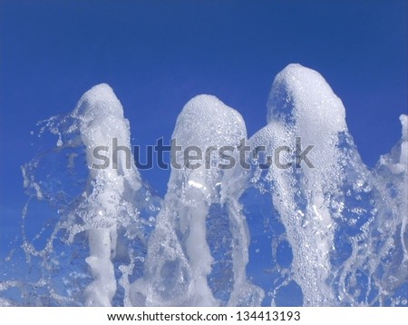 Close view on the foamy fountain water top with blue sky in the background/Water foam