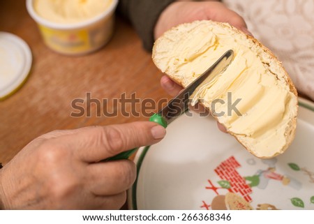 Woman spreading butter on slice of breath in the kitchen