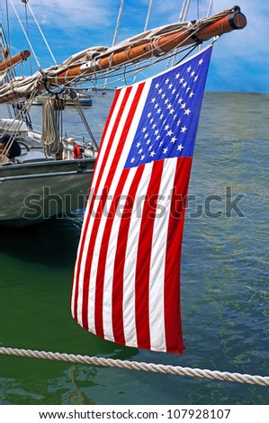 an american flag hanging of the outhaul on a yacht an american flag hanging of the outhaul on a yacht