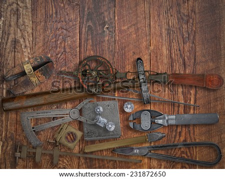 vintage jeweler tools and diamonds over wooden working bench, space for text