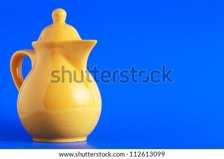 Nice yellow ceramic milk jug on blue background
