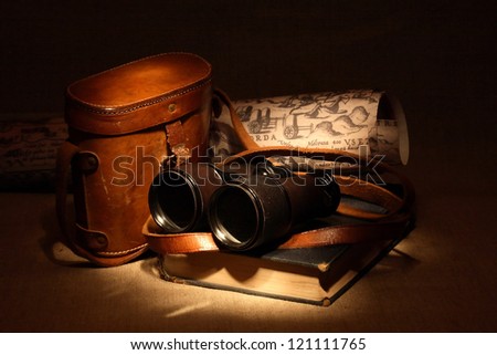 Still life with old binoculars on ancient book near leather case